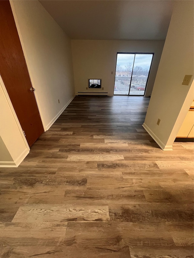 spare room with baseboards, wood finished floors, and baseboard heating