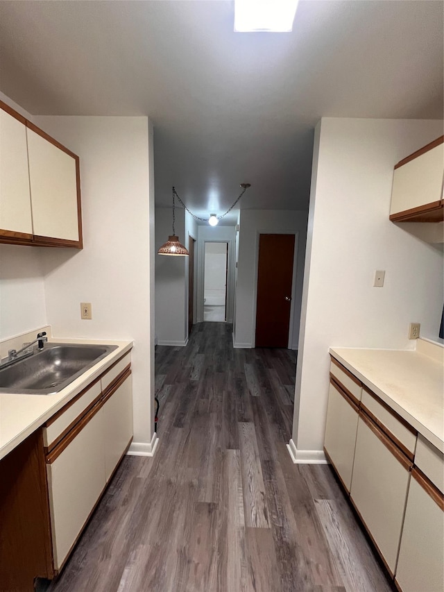 kitchen with a sink, dark wood finished floors, white cabinetry, and light countertops