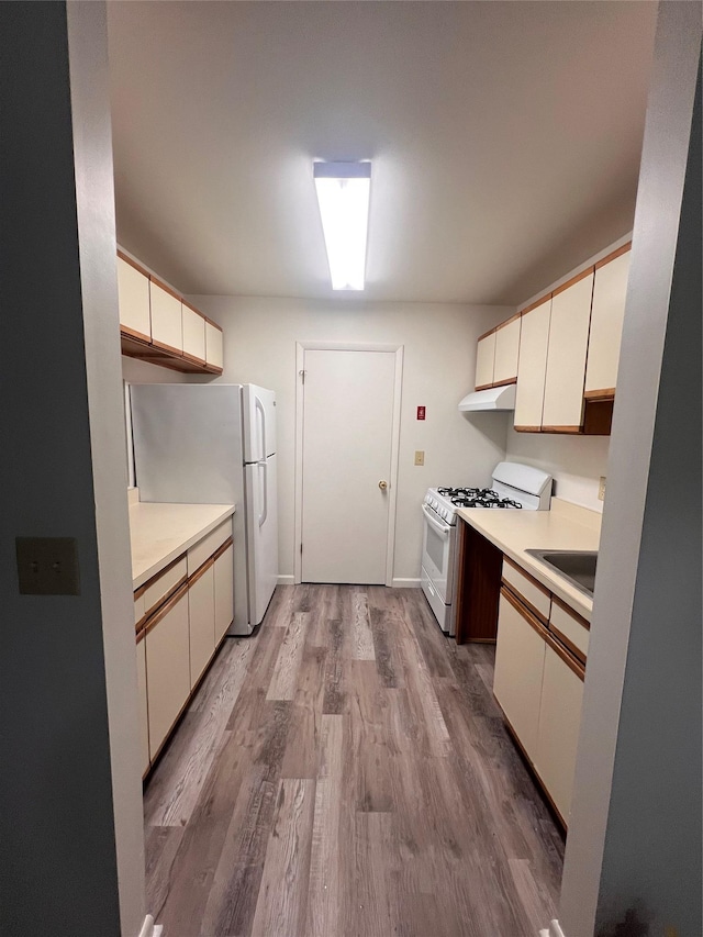 kitchen with wood finished floors, light countertops, white cabinets, under cabinet range hood, and white appliances