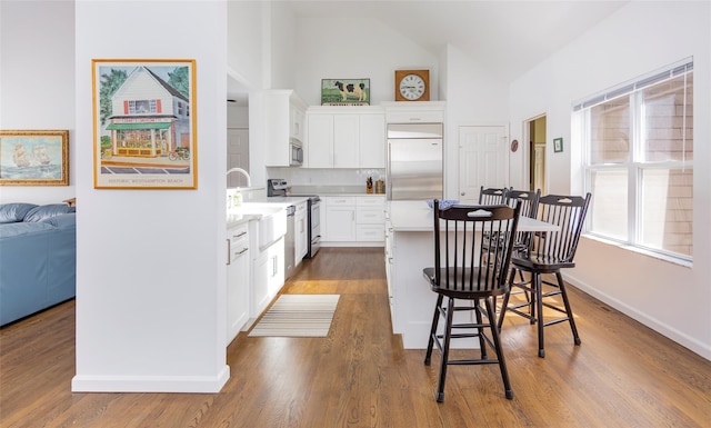 81 Lakeside Ln, Westhampton, NY 11977 - kitchen featuring appliances with stainless steel finishes, light countertops, a kitchen breakfast bar, high vaulted ceiling, and a kitchen island