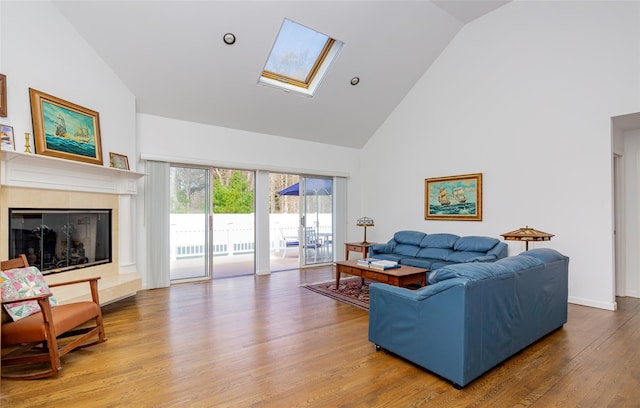 81 Lakeside Ln, Westhampton, NY 11977 - living room with high vaulted ceiling, a glass covered fireplace, a skylight, and wood finished floors