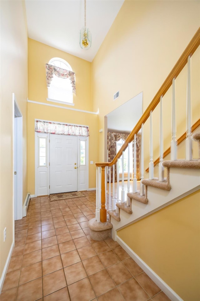 entrance foyer with a high ceiling, a baseboard radiator, baseboards, stairway, and light tile patterned floors