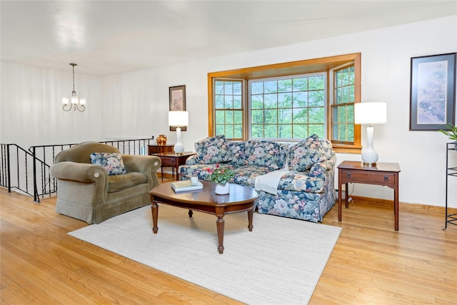 living area with baseboards, a notable chandelier, and wood finished floors