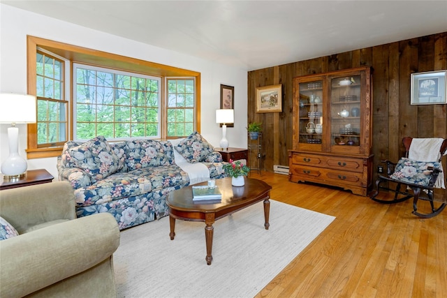 living area with wooden walls, baseboard heating, and light wood-style flooring