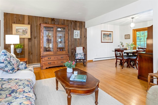 living room with a baseboard heating unit, wood walls, and light wood-type flooring