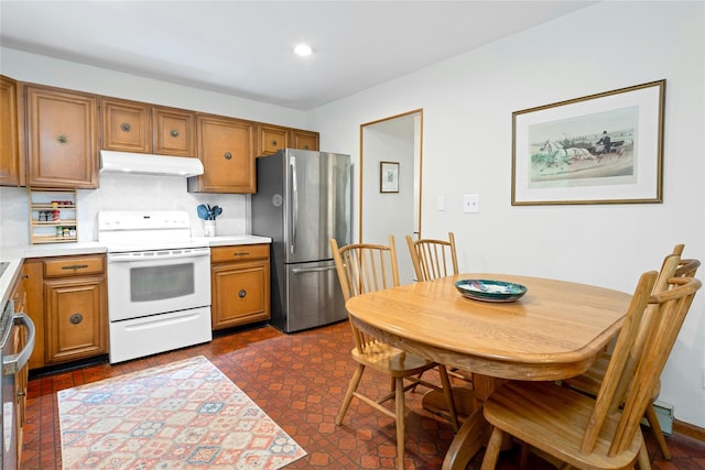 kitchen featuring brown cabinets, freestanding refrigerator, electric stove, under cabinet range hood, and light countertops