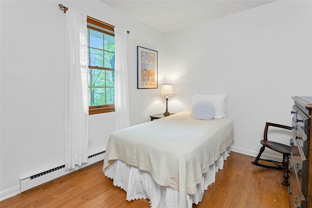 bedroom with baseboards, wood finished floors, and baseboard heating