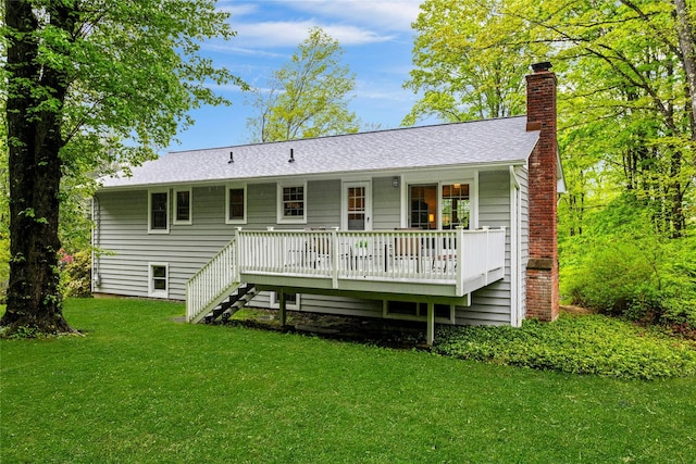back of house featuring a chimney, a yard, stairs, a deck, and roof with shingles