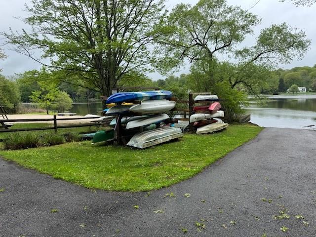view of vehicle parking with fence and a water view