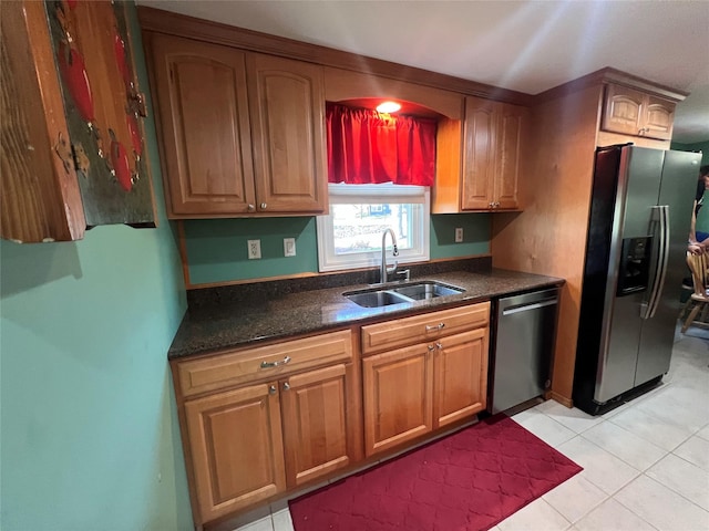 kitchen featuring a sink, light tile patterned floors, dark countertops, and stainless steel appliances