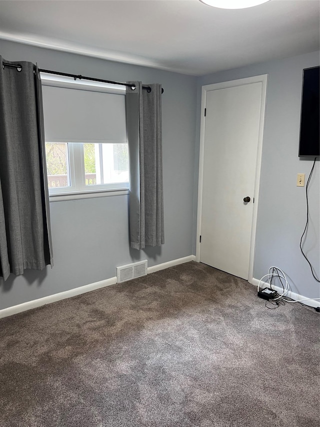 empty room with baseboards, visible vents, and carpet