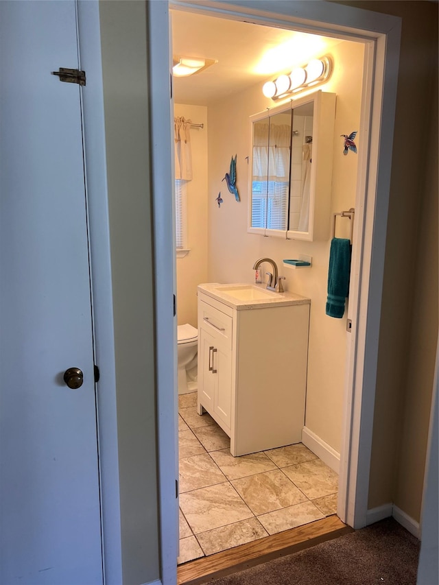 bathroom with vanity, baseboards, and toilet