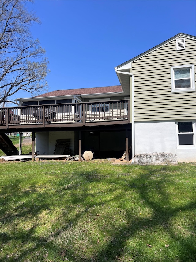 back of house featuring a lawn, a shingled roof, a wooden deck, and stairway