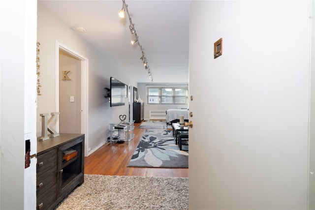 hall featuring baseboards, radiator, and wood finished floors