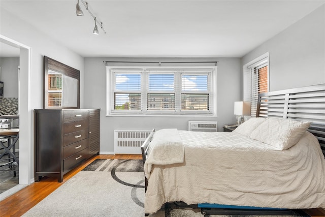 bedroom with radiator, wood finished floors, and baseboards