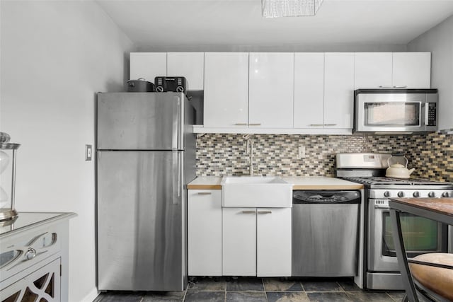 kitchen featuring a sink, stainless steel appliances, tasteful backsplash, light countertops, and white cabinets