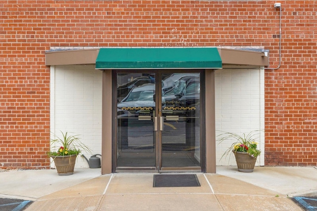 property entrance featuring brick siding and french doors