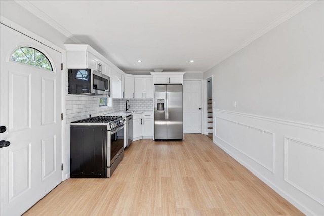 kitchen featuring a sink, light wood-type flooring, white cabinetry, light countertops, and appliances with stainless steel finishes