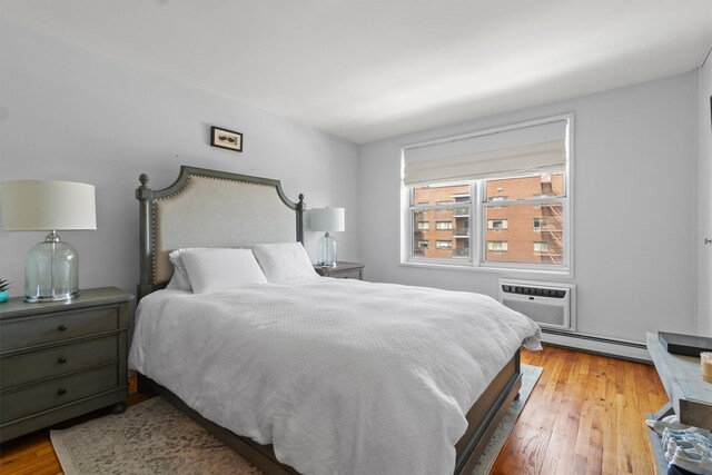 377 Westchester Ave Unit 6C, Port Chester, NY 10573 - bedroom with a baseboard heating unit, wood finished floors, and an AC wall unit