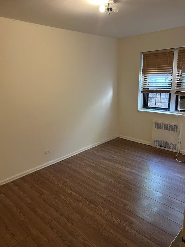 83-75 118th St Unit 4H, Kew Gardens, NY 11415 - unfurnished room with radiator heating unit, dark wood-type flooring, baseboards, and cooling unit