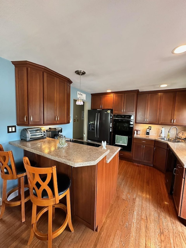 33 41st St, Islip, NY 11751 - kitchen with a peninsula, light wood-type flooring, light stone counters, a sink, and black appliances