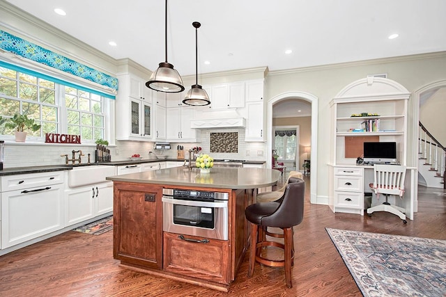 kitchen with a center island, a sink, tasteful backsplash, and ornamental molding