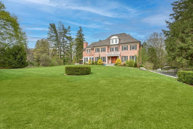 view of front of house featuring a chimney and a front yard