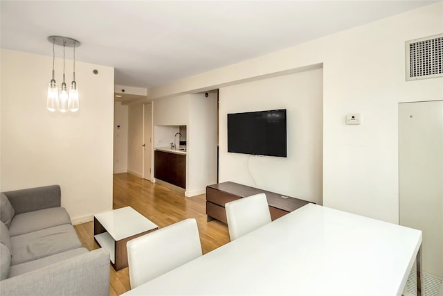 living area with baseboards, visible vents, and light wood finished floors