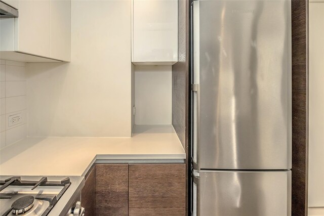 kitchen featuring light countertops, modern cabinets, freestanding refrigerator, and white cabinets