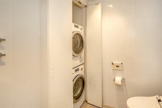 laundry area featuring stacked washer and dryer, laundry area, and tile walls