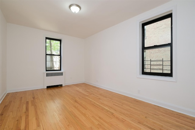 spare room with baseboards, light wood finished floors, and radiator heating unit