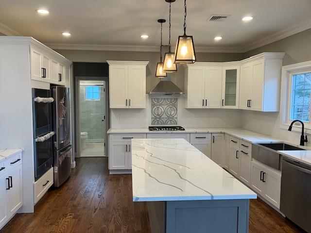 267 N Elm St, Massapequa, NY 11758 - kitchen featuring stainless steel appliances, a sink, a center island, wall chimney exhaust hood, and white cabinets