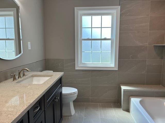 267 N Elm St, Massapequa, NY 11758 - full bathroom with tile walls, a tub, vanity, and toilet