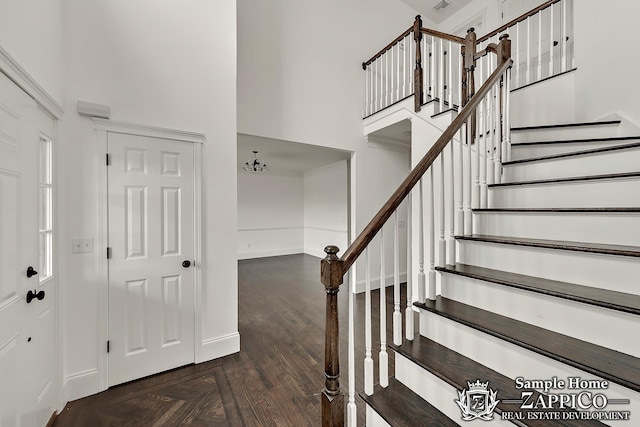 stairs with visible vents, baseboards, a towering ceiling, and parquet floors