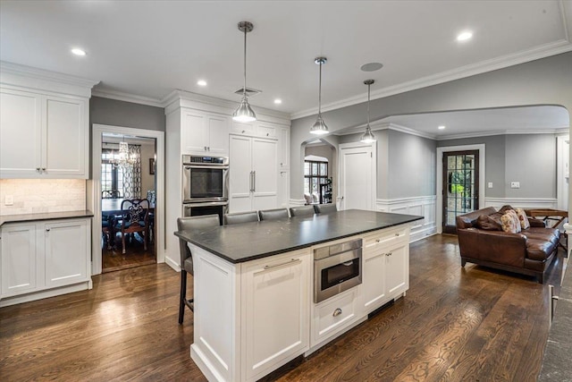 kitchen with built in microwave, arched walkways, dark countertops, double oven, and dark wood-style floors