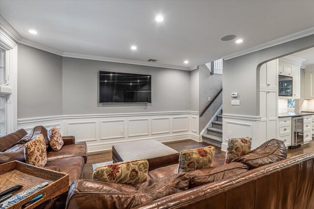 living area featuring stairway, crown molding, dark wood-type flooring, and beverage cooler