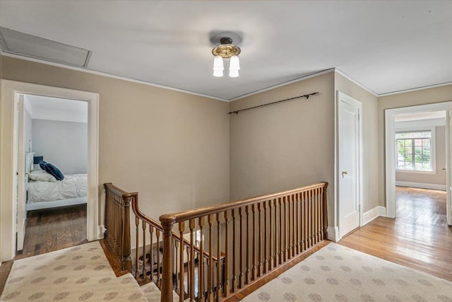 corridor featuring baseboards, visible vents, crown molding, wood finished floors, and an upstairs landing