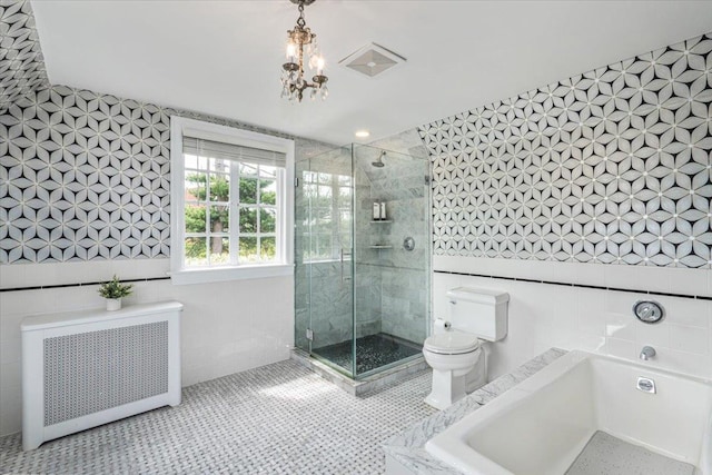 bathroom with a stall shower, tile walls, radiator, and a garden tub