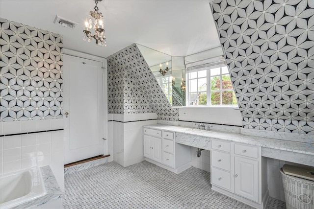 bathroom with tile walls, vanity, visible vents, a chandelier, and a garden tub