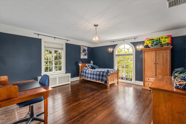 bedroom with radiator, wood finished floors, visible vents, an inviting chandelier, and baseboards