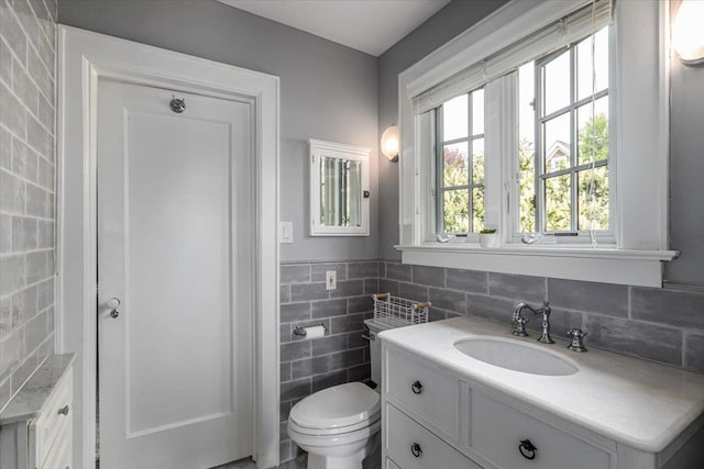 bathroom featuring toilet, tile walls, and vanity