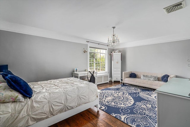 bedroom with radiator, a notable chandelier, visible vents, and wood finished floors