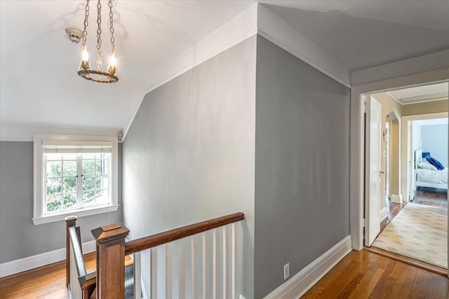 hall with lofted ceiling, baseboards, an upstairs landing, and wood finished floors