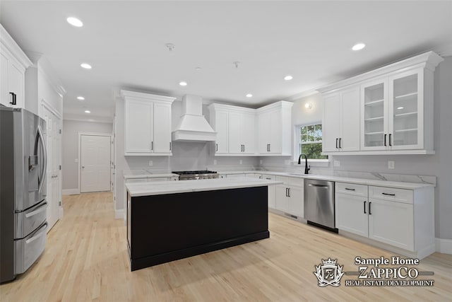 kitchen featuring a sink, premium range hood, a kitchen island, stainless steel appliances, and light wood-type flooring