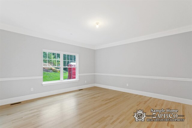 spare room with baseboards, crown molding, visible vents, and wood finished floors