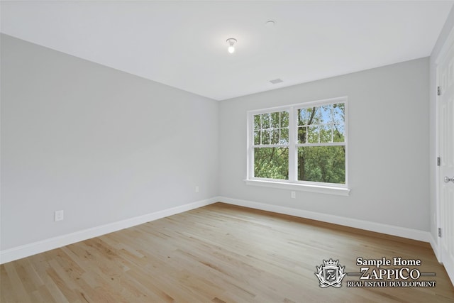 spare room with baseboards and wood finished floors