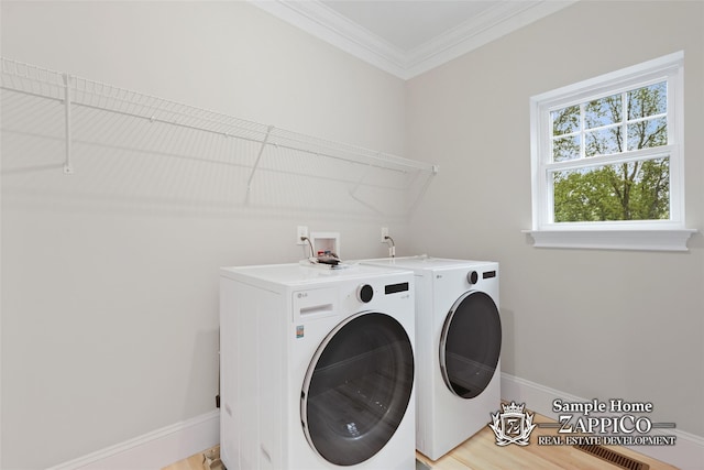 washroom featuring washer and clothes dryer, laundry area, crown molding, light wood-style flooring, and baseboards