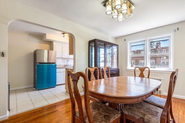 150-20 77th Ave, Kew Garden Hills, NY 11367 - dining room featuring baseboards, arched walkways, light wood-style flooring, and a chandelier