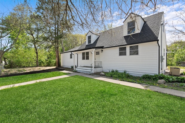 cape cod home featuring roof with shingles and a front yard