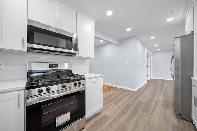 kitchen with appliances with stainless steel finishes, light wood-style flooring, white cabinetry, baseboards, and decorative backsplash